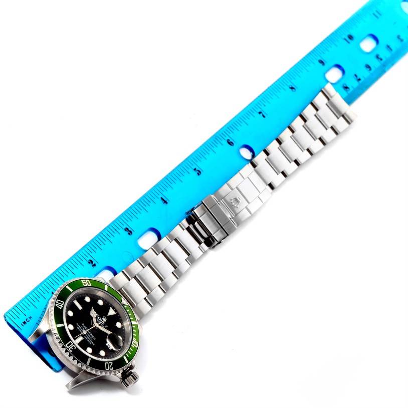 The image shows a Rolex Submariner 16610LV Men
s Stainless Steel Black Dial 16610LV Men
s Stainless Steel Black Dial watch face and stainless steel bracelet partially measured with a blue ruler.