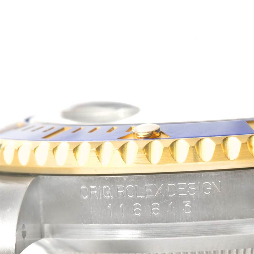 This image shows a close-up of the Rolex Submariner 116613 Men's Steel and Gold (two tone) Blue Dial 116613 Men's Steel and Gold (two tone) Blue Dial's bezel and part of the case, highlighting the model number and "ORIG. ROLEX DESIGN" engraving.