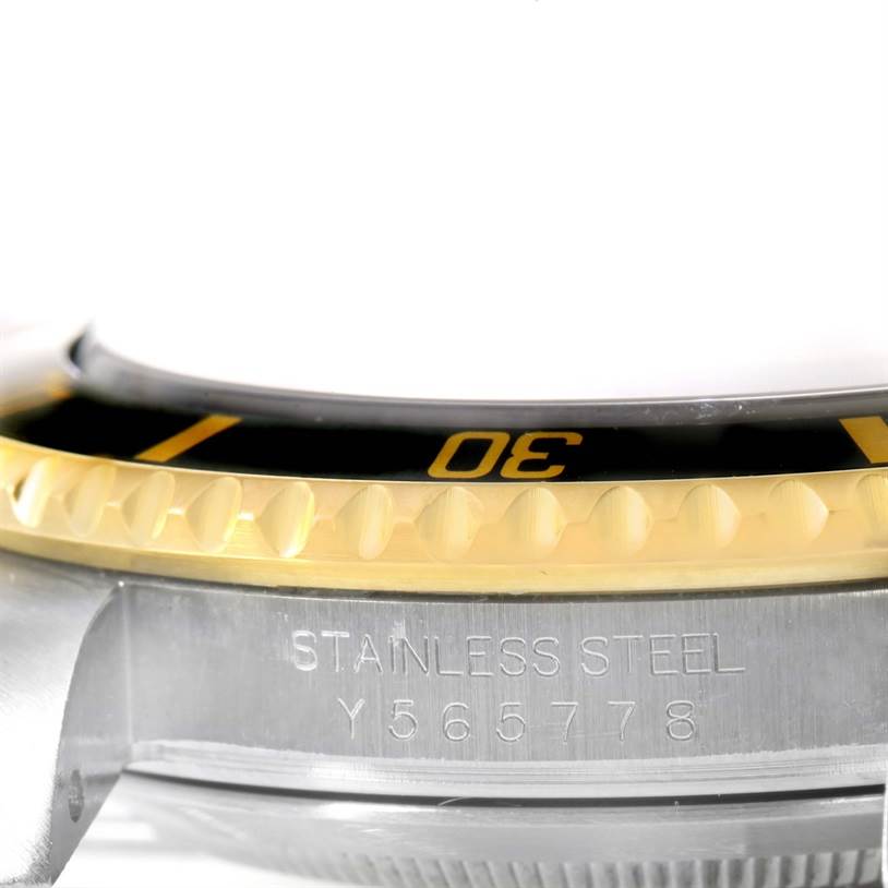 The image shows a close-up of the bezel and engraved side of a Submariner model watch by Rolex.