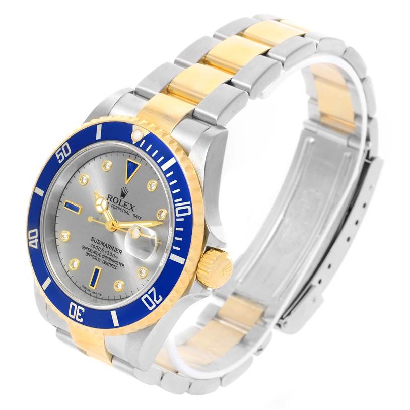 This image shows a Rolex Submariner 16613 Men's Steel and Gold (two tone) Grey Dial 16613 Men's Steel and Gold (two tone) Grey Dial watch angled from above, highlighting its blue bezel, gold and silver band, face, and crown.