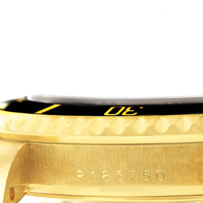 This close-up angle of the Rolex Submariner 16618 Men
s Yellow Gold Black Dial 16618 Men
s Yellow Gold Black Dial shows the golden bezel with the "30" minute marker and part of the case with its serial number.