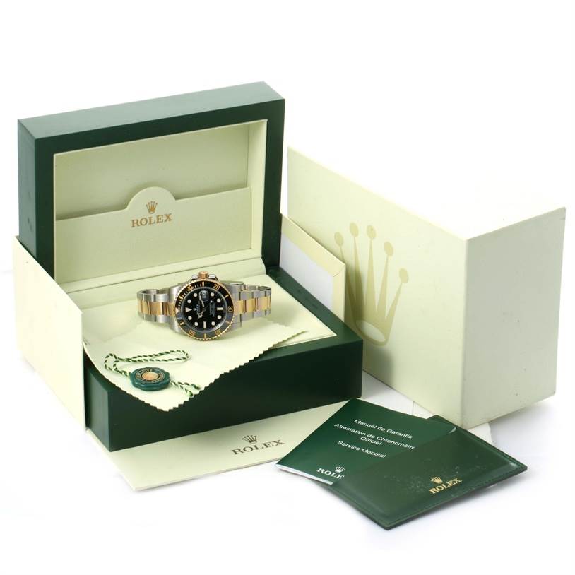 The image shows a Rolex Submariner 116613 Men
s Steel and Gold (two tone) Black Dial 116613 Men
s Steel and Gold (two tone) Black Dial watch in its open box with accompanying booklets and accessories.