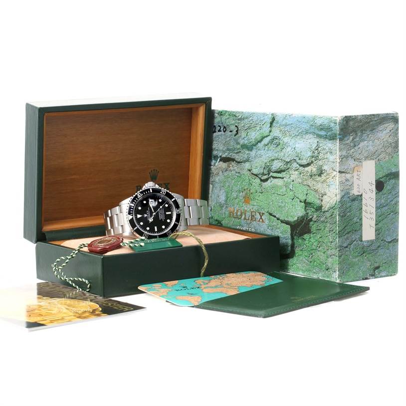 The image shows a Rolex Submariner 16610 Men
s Stainless Steel Black Dial 16610 Men
s Stainless Steel Black Dial watch displayed in its open box, alongside its outer box and accompanying documents and tags.
