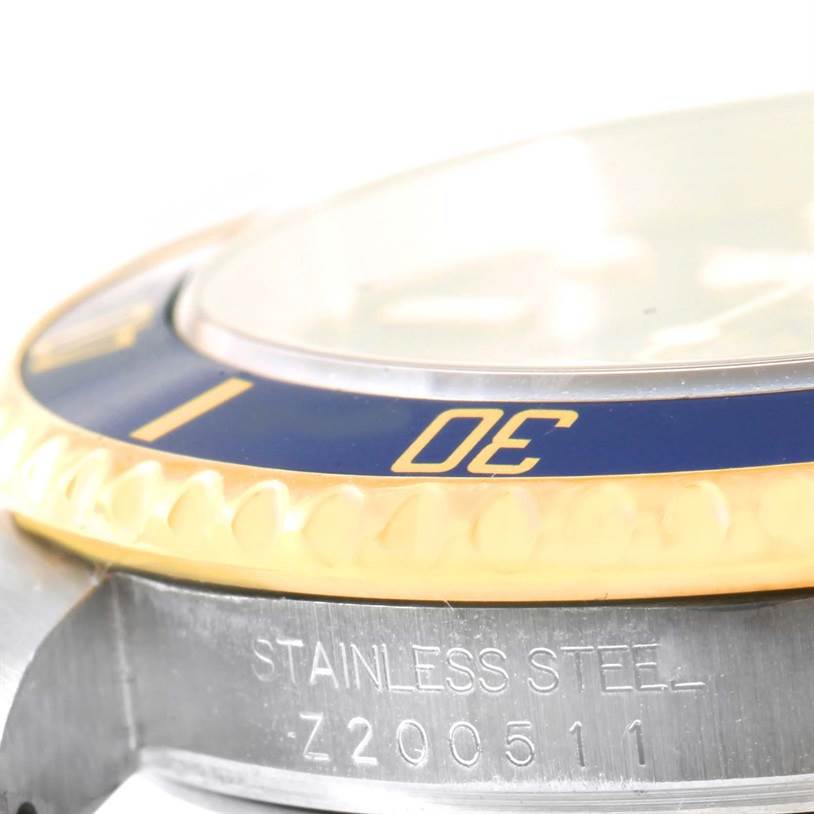 This close-up image of the Rolex Submariner 16613 Men
s Steel and Gold (two tone) Black Dial 16613 Men
s Steel and Gold (two tone) Black Dial watch shows the side edge, bezel, and part of the crystal, with "STAINLESS STEEL" engraved.