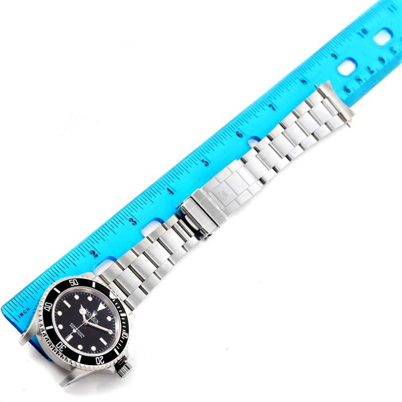 The image shows a top-down view of a Rolex Submariner 14060 Men
s Stainless Steel Black Dial 14060 Men
s Stainless Steel Black Dial watch laid beside a blue ruler.