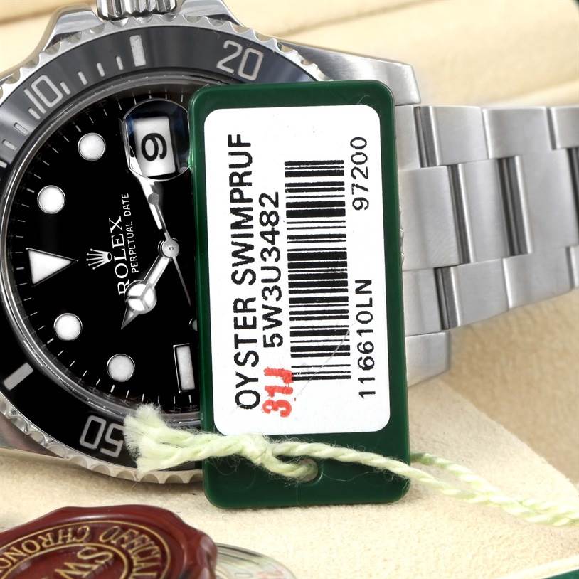 A close-up shot of a Rolex Submariner 116610 Men
s Stainless Steel Black Dial 116610 Men
s Stainless Steel Black Dial watch, showing part of the bezel, dial, bracelet, and an Oyster Swimpruf tag.