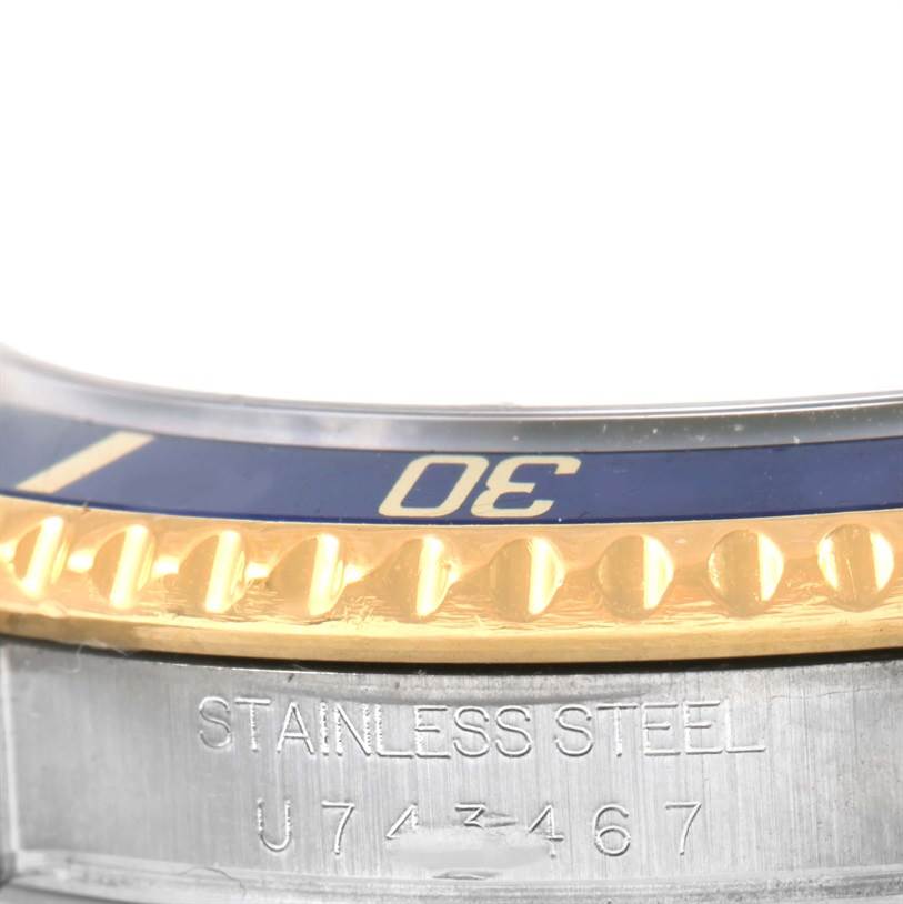 This close-up of a Rolex Submariner 16613 Men
s Steel and Gold (two tone) Black Dial 16613 Men
s Steel and Gold (two tone) Black Dial watch shows part of the bezel and the engraved stainless steel case with the serial number.