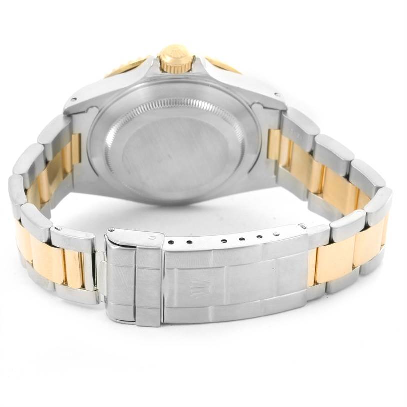 The image shows the backside of a Rolex Submariner 16613 Men
s Steel and Gold (two tone) Black Dial 16613 Men
s Steel and Gold (two tone) Black Dial watch, focusing on its clasp, bracelet, and case back.