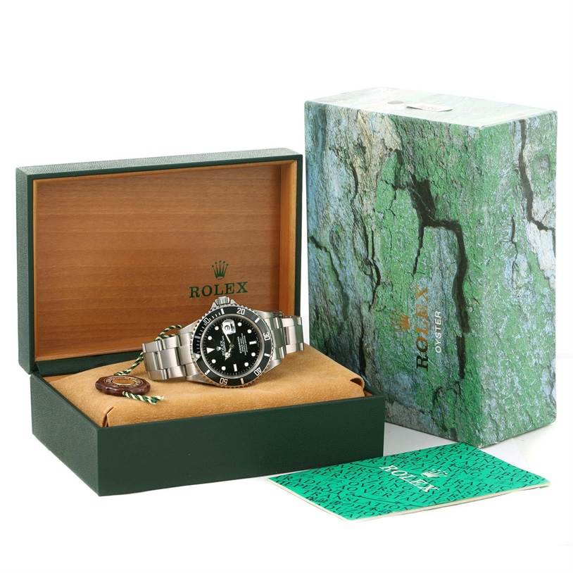 The image shows a Rolex Submariner 16610 Men
s Stainless Steel Black Dial 16610 Men
s Stainless Steel Black Dial, displayed in an open box with its accessories, including the outer box and manual.