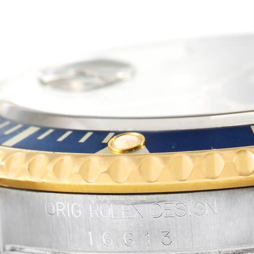 This close-up angle of the Rolex Submariner 16613 Men's Steel and Gold (two tone) Blue Dial 16613 Men's Steel and Gold (two tone) Blue Dial shows part of the bezel, crown, and model engraving.