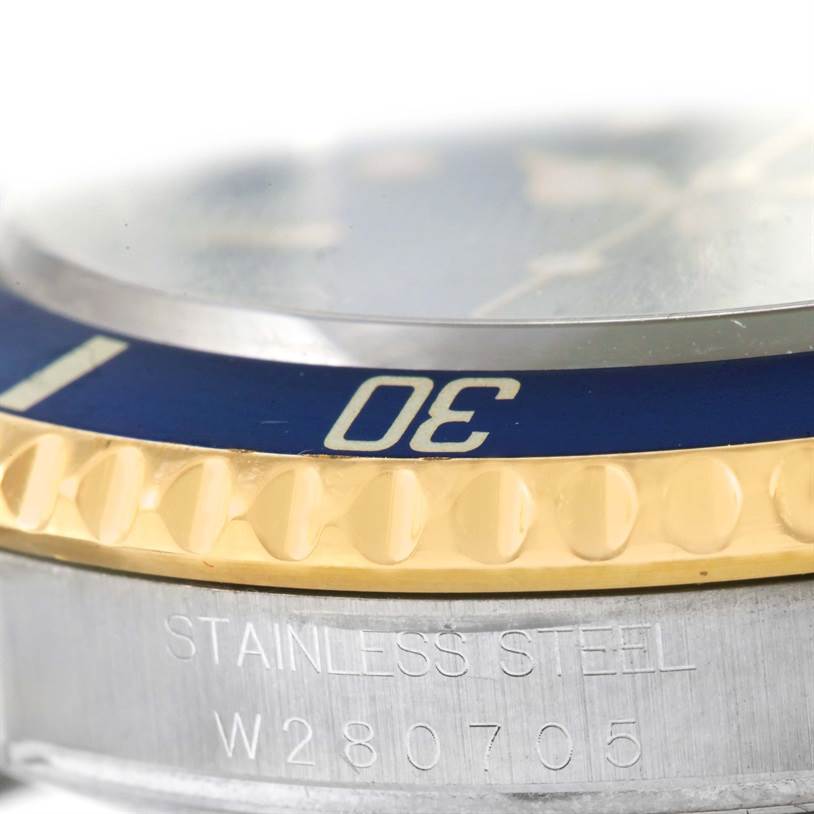 The image shows a close-up side view of a Rolex Submariner 16613 Men's Steel and Gold (two tone) Blue Dial 16613 Men's Steel and Gold (two tone) Blue Dial watch, highlighting the blue bezel, gold ridged edge, and part of the stainless steel case.