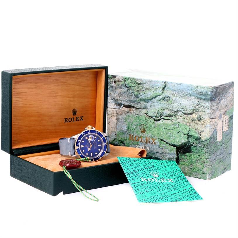 The Rolex Submariner 16613 Men's Steel and Gold (two tone) Blue Dial 16613 Men's Steel and Gold (two tone) Blue Dial watch is shown in an open display box at a front angle, with the outer box, tags, and paperwork visible.