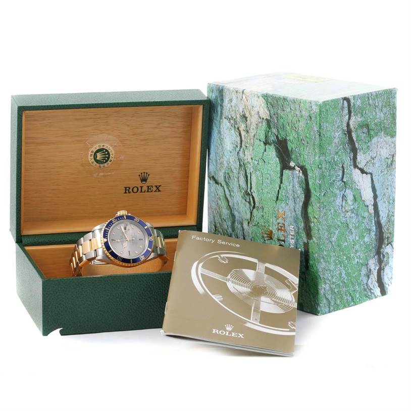 The image shows a Rolex Submariner 16613 Men
s Steel and Gold (two tone) Grey Dial 16613 Men
s Steel and Gold (two tone) Grey Dial watch in its open box, with a factory service booklet and outer packaging.