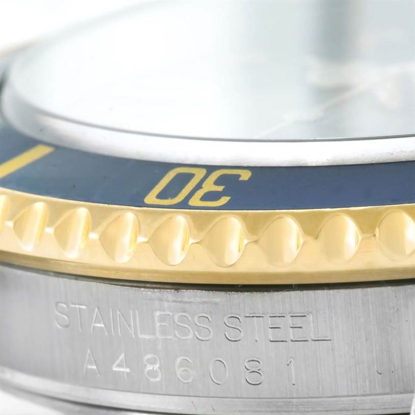 The image shows a close-up of the bezel and the stainless steel side of the Rolex Submariner 16613 Men
s Steel and Gold (two tone) Grey Dial 16613 Men
s Steel and Gold (two tone) Grey Dial watch, with part of the serial number visible.