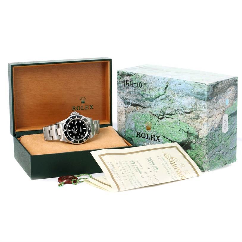 The image shows a front view of a Rolex Submariner 14060 Men
s Stainless Steel Black Dial 14060 Men
s Stainless Steel Black Dial watch in its open box, accompanied by its outer box and papers.
