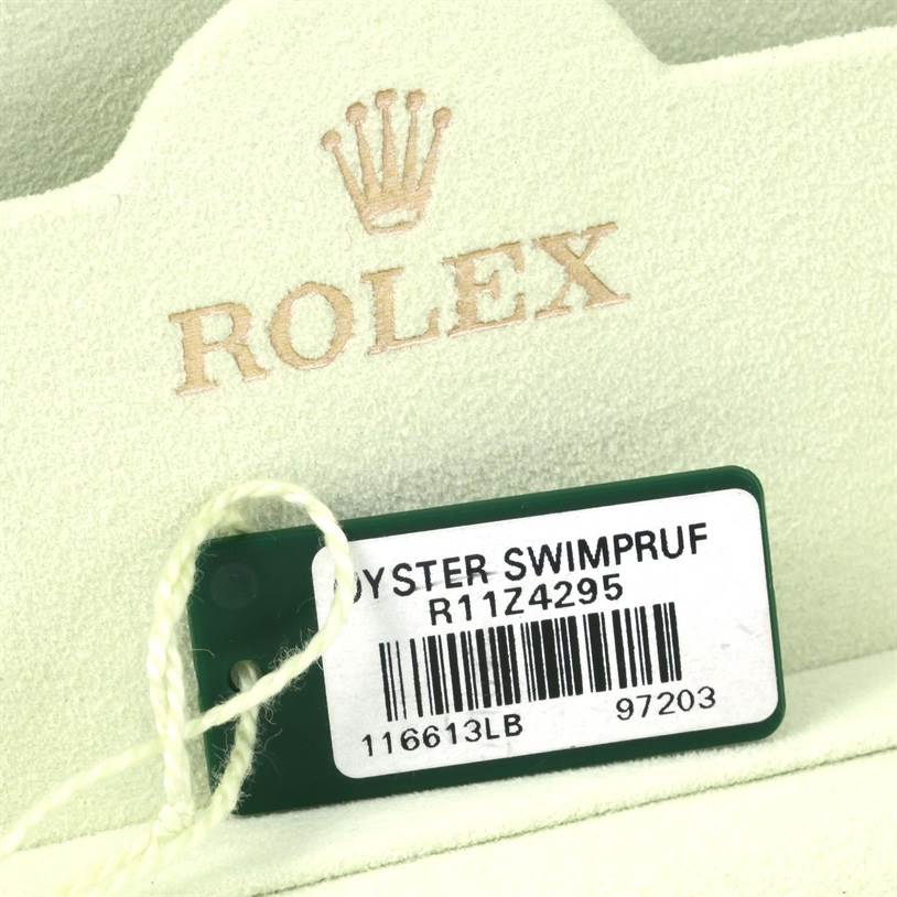 The image shows a close-up of a label and packaging for a Rolex Submariner 116613 Men's Steel and Gold (two tone) Blue Dial 116613 Men's Steel and Gold (two tone) Blue Dial Oyster watch.