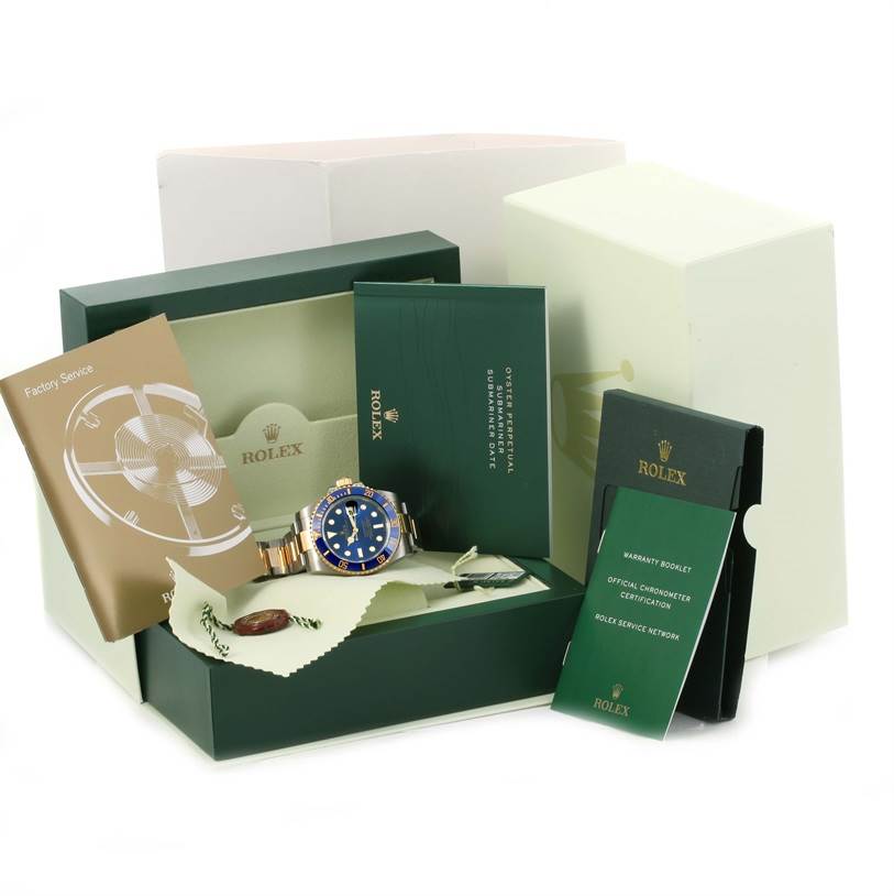 The image shows a Rolex Submariner 116613 Men's Steel and Gold (two tone) Blue Dial 116613 Men's Steel and Gold (two tone) Blue Dial watch with its box, warranty booklet, factory service manual, and other packaging accessories.