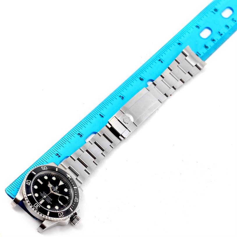 The image shows a Rolex Submariner 116610 Men
s Stainless Steel Black Dial 116610 Men
s Stainless Steel Black Dial watch laid flat with a blue ruler measuring its length.