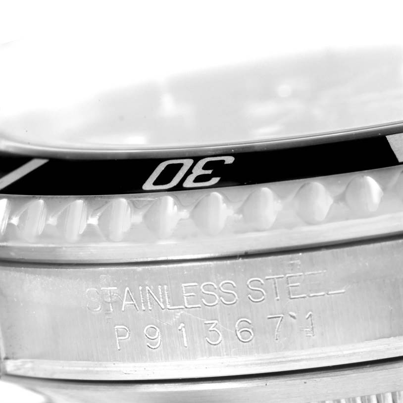 This image shows a close-up of the bezel and part of the case of the Rolex Submariner 16610 Men
s Stainless Steel Black Dial 16610 Men
s Stainless Steel Black Dial, highlighting the "30" mark and "STAINLESS STEEL" engraving.
