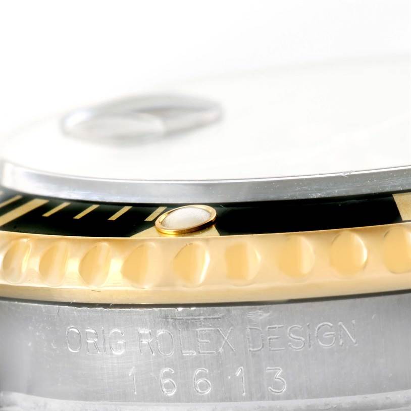 The image shows a close-up of the bezel and case of a Rolex Submariner 16613 Men's Steel and Gold (two tone) Black Dial 16613 Men's Steel and Gold (two tone) Black Dial watch, highlighting the engraving "ORIG ROLEX DESIGN 16613."