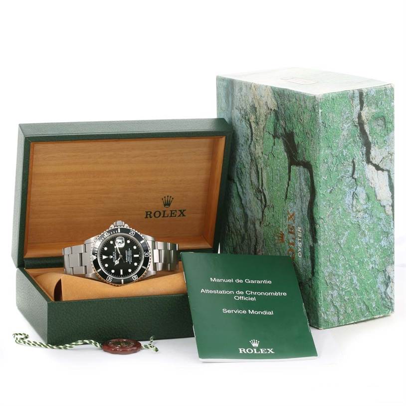 The Rolex Submariner 16610 Men
s Stainless Steel Black Dial 16610 Men
s Stainless Steel Black Dial watch is shown front-on, inside its open case with accompanying manuals and outer box.