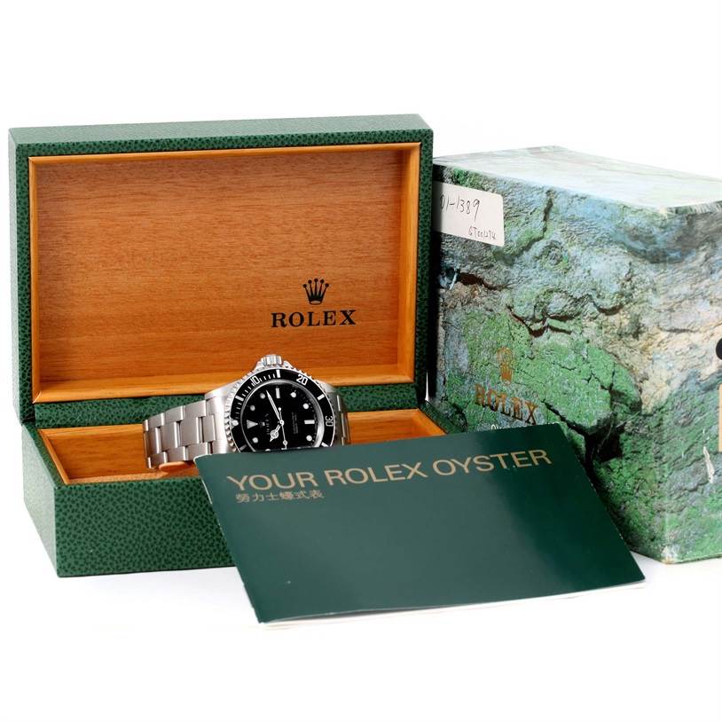 This image shows a Rolex Submariner 14060 Men
s Stainless Steel Black Dial 14060 Men
s Stainless Steel Black Dial watch placed in its open wooden and green Rolex box alongside the outer box and a booklet.