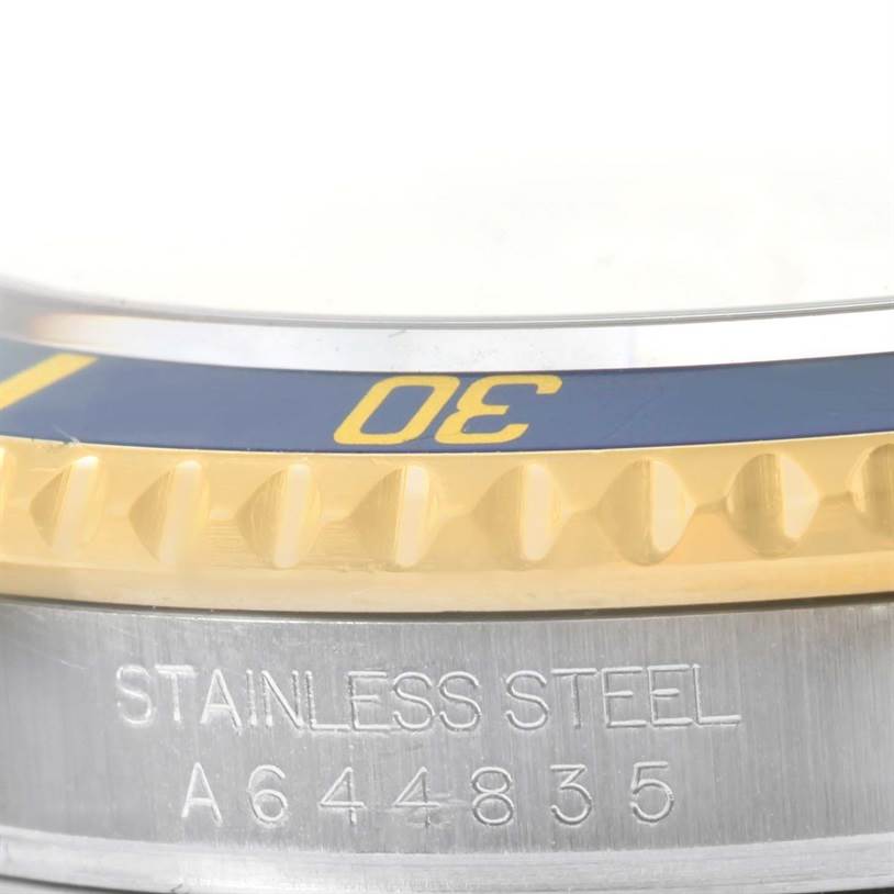 This image shows a side view of the bezel and case of a Rolex Submariner 16613 Men's Steel and Gold (two tone) Grey Dial 16613 Men's Steel and Gold (two tone) Grey Dial watch, highlighting the model's serial number and "STAINLESS STEEL" engraving.