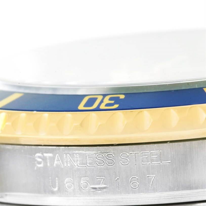 This close-up image of a Rolex Submariner 16613 Men's Steel and Gold (two tone) Grey Dial 16613 Men's Steel and Gold (two tone) Grey Dial shows the side view of the bezel and case, highlighting the stainless steel and serial number.