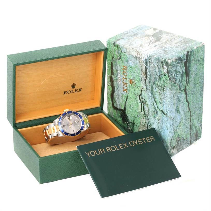 The image shows a Rolex Submariner 16613 Men's Steel and Gold (two tone) Grey Dial 16613 Men's Steel and Gold (two tone) Grey Dial watch in its open green and wooden box, alongside the outer box and an instruction booklet.