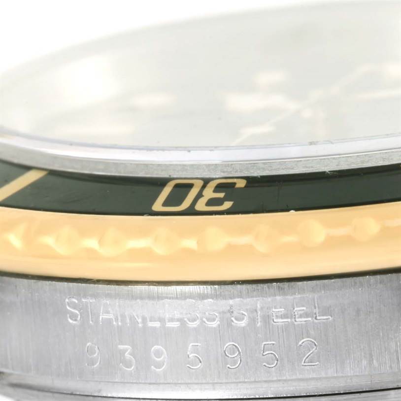 Close-up side view of a Rolex Submariner 16803 Men
s Steel and Gold (two tone) Black Dial 16803 Men
s Steel and Gold (two tone) Black Dial watch, showing part of the bezel with "30" marking, textured edge, and a stainless steel case with serial number.