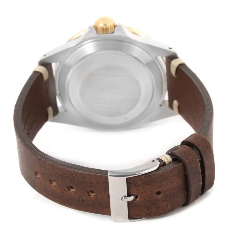 The image shows a rear view of a Rolex Submariner 16803 Men
s Steel and Gold (two tone) Black Dial 16803 Men
s Steel and Gold (two tone) Black Dial watch, focusing on the case back and leather strap with a metal buckle.