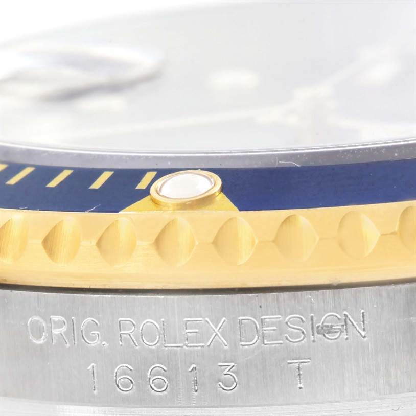 The image shows a close-up of the side view of a Rolex Submariner 16613 Men's Steel and Gold (two tone) Blue Dial 16613 Men's Steel and Gold (two tone) Blue Dial watch, highlighting the bezel and engraved model number.