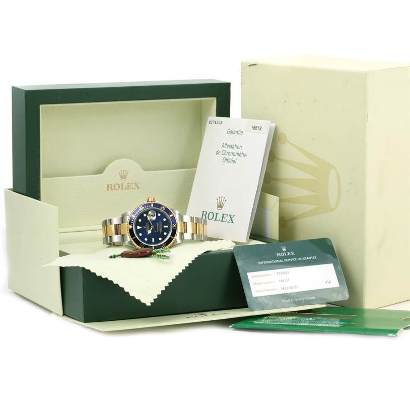 The image shows a Rolex Submariner 16613 Men's Steel and Gold (two tone) Blue Dial 16613 Men's Steel and Gold (two tone) Blue Dial watch with a blue dial and gold accents, along with its box and authenticity documents.