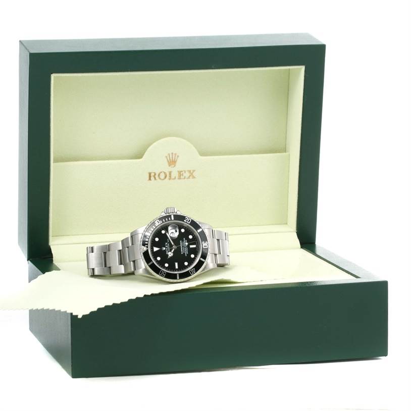 The Rolex Submariner 16610 Men
s Stainless Steel Black Dial 16610 Men
s Stainless Steel Black Dial watch is displayed at a front angle in its open, green box bearing the Rolex logo.