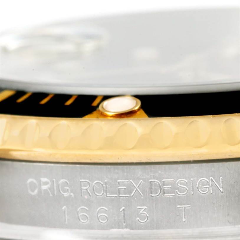 This image shows a close-up of the Rolex Submariner 16613 Men's Steel and Gold (two tone) Black Dial 16613 Men's Steel and Gold (two tone) Black Dial's bezel and side case, highlighting the model number and "Rolex Design" engraving.