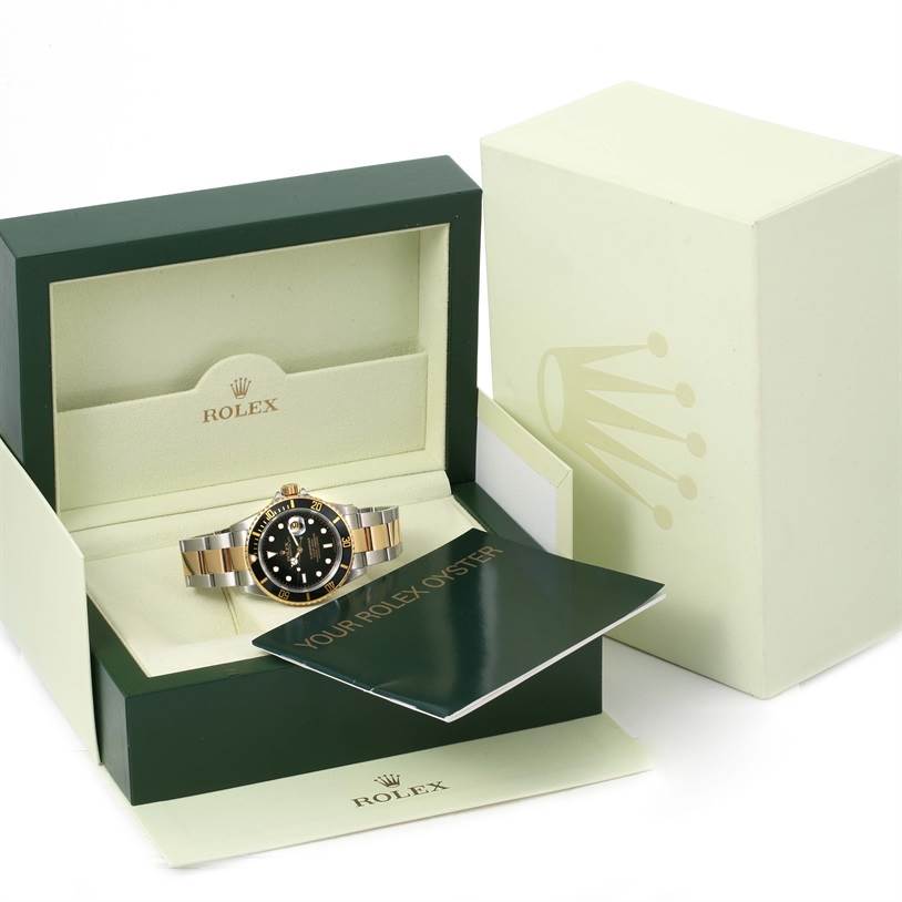 This image shows a Rolex Submariner 16613 Men's Steel and Gold (two tone) Black Dial 16613 Men's Steel and Gold (two tone) Black Dial watch in its box with documentation and outer packaging on display.