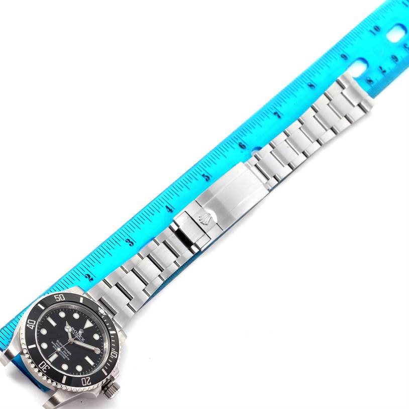 The image shows the front view of a Rolex Submariner 114060 Men
s Stainless Steel Black Dial 114060 Men
s Stainless Steel Black Dial watch, including its bezel, dial, and bracelet with clasp, next to a ruler.