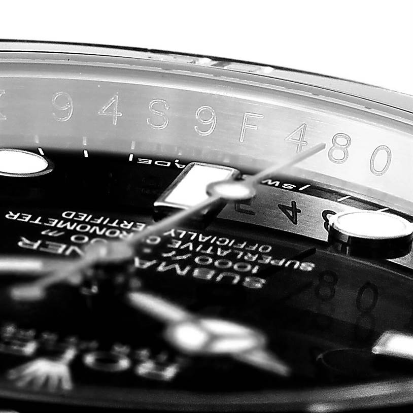 The image shows a close-up of the dial, hands, and rehaut with engraved serial numbers of the Submariner model by Rolex.