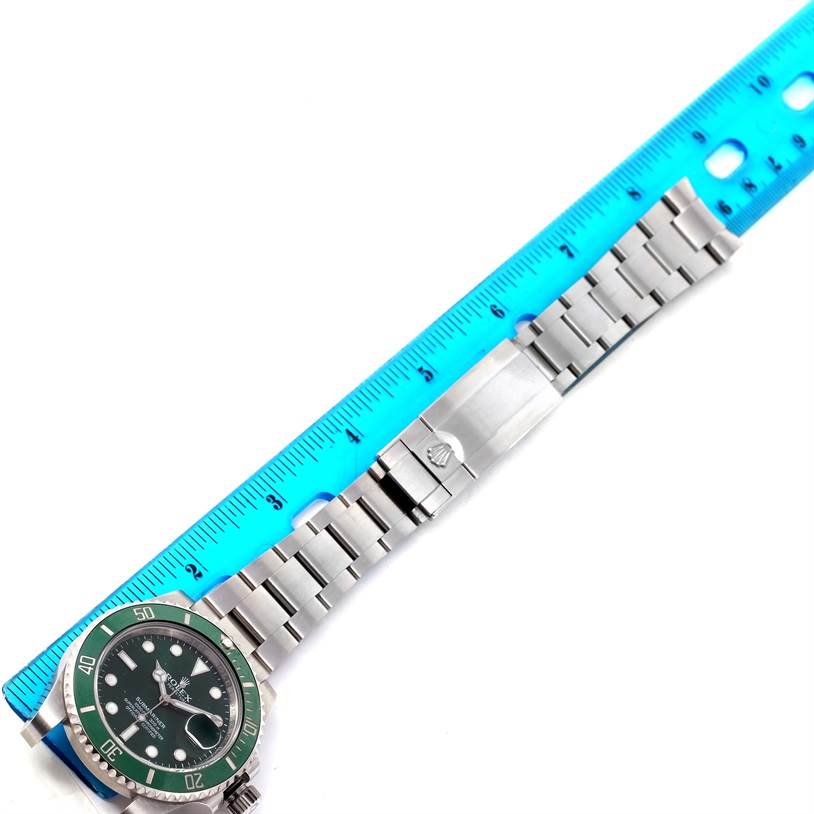 The image shows a top-down view of a Rolex Submariner 116610LV Men's Stainless Steel Green Dial 116610LV Men's Stainless Steel Green Dial watch, highlighting its face, bezel, and bracelet laid next to a blue ruler.