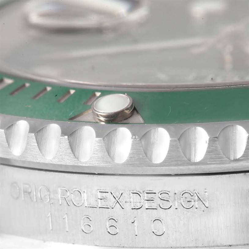 This close-up image of a Rolex Submariner 116610LV Men's Stainless Steel Green Dial 116610LV Men's Stainless Steel Green Dial watch shows part of the green bezel, lume pip, and engraved model number (116610).
