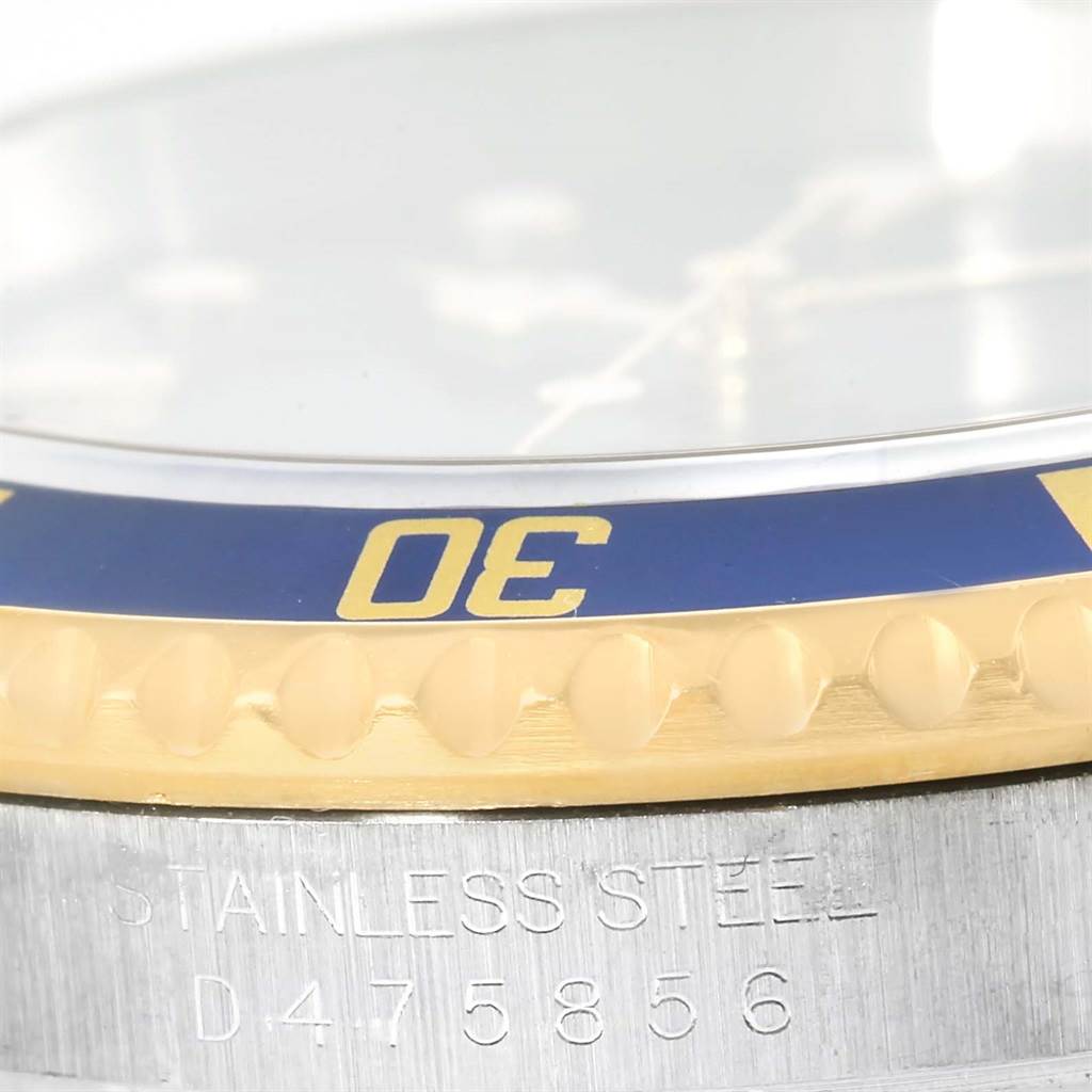 This close-up image of the Rolex Submariner 16613 Men
s Steel and Gold (two tone) Blue Dial 16613 Men
s Steel and Gold (two tone) Blue Dial shows the watch
s bezel, case, and part of the serial number on its stainless steel surface.