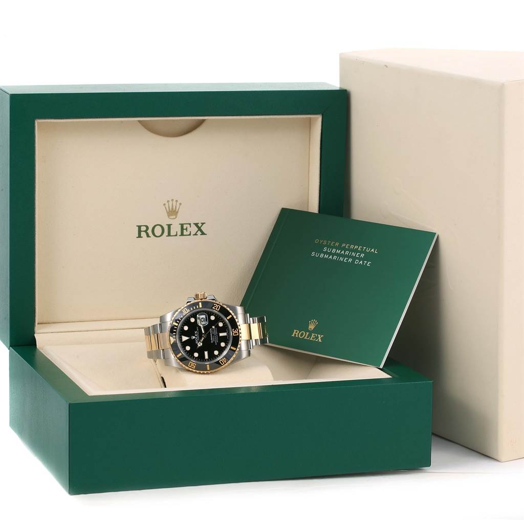The image shows a Rolex Submariner 116613LN Men
s Steel and Gold (two tone) Black Dial 116613LN Men
s Steel and Gold (two tone) Black Dial watch placed inside its green and beige box with a warranty certificate booklet.