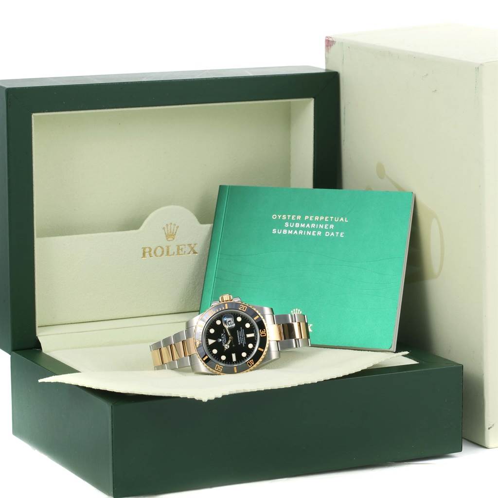 The image shows a Rolex Submariner 116613 Men
s Steel and Gold (two tone) Black Dial 116613 Men
s Steel and Gold (two tone) Black Dial watch with its box and instruction manual, positioned at a frontal angle.