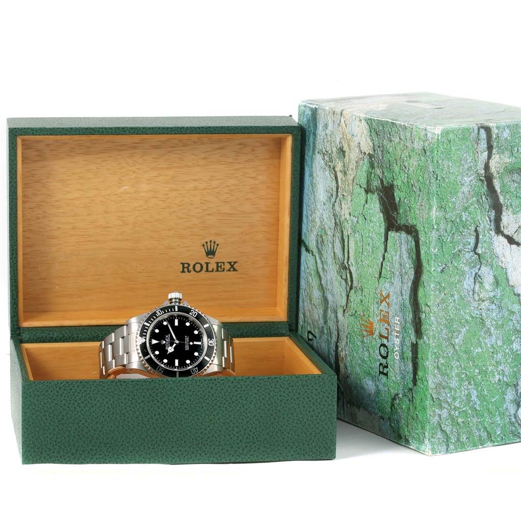 The Rolex Submariner 14060 Men's Stainless Steel Black Dial 14060 Men's Stainless Steel Black Dial watch is shown front-facing in its open green box, next to its green marbled outer box.