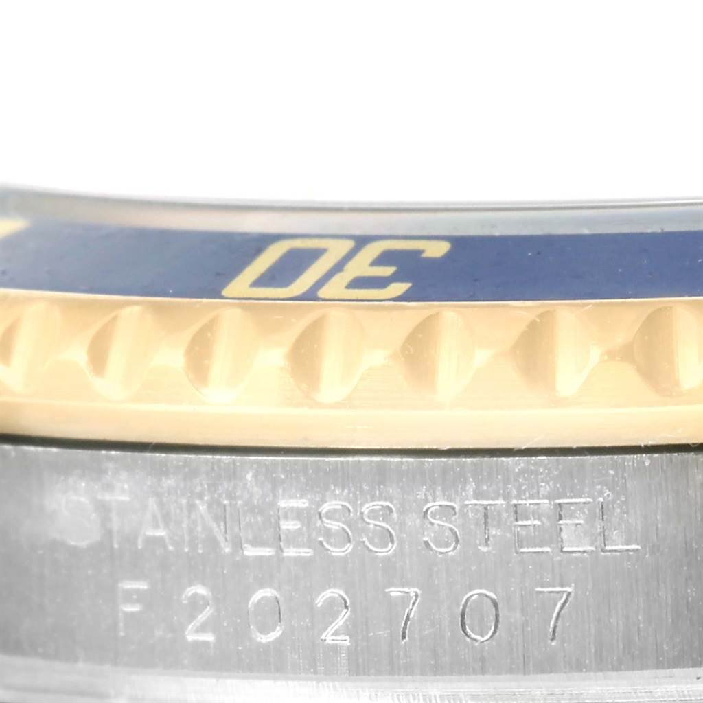This close-up image of the Rolex Submariner 16613 Men
s Steel and Gold (two tone) Blue Dial 16613 Men
s Steel and Gold (two tone) Blue Dial shows part of the bezel and the engraved serial number on the stainless steel case.
