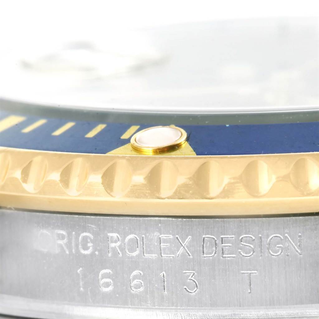 This close-up image of a Rolex Submariner 16613 Men
s Steel and Gold (two tone) Blue Dial 16613 Men
s Steel and Gold (two tone) Blue Dial watch shows the engraved model number and the edge of the bezel with its detailing.