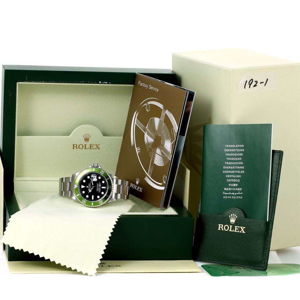The image shows a Rolex Submariner 16610LV Men
s Stainless Steel Black Dial 16610LV Men
s Stainless Steel Black Dial watch with its box, manuals, and accessories from a front angle.
