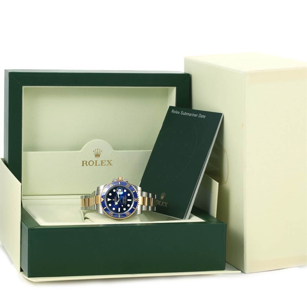 The Rolex Submariner 116613 Men
s Steel and Gold (two tone) Blue Dial 116613 Men
s Steel and Gold (two tone) Blue Dial watch is shown front-on, placed in its open box with a manual beside it.