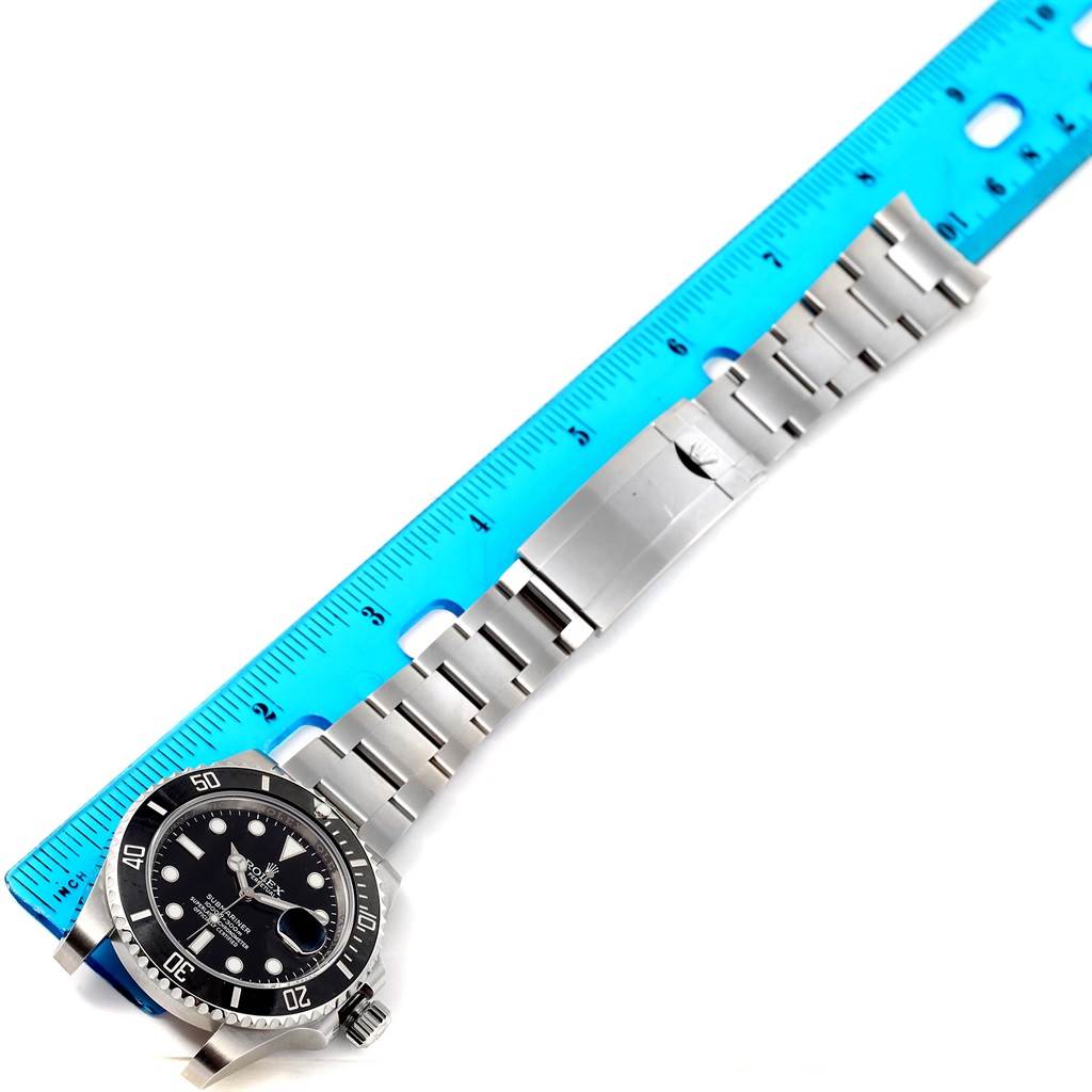 The image shows a Rolex Submariner 116610 Men
s Stainless Steel Black Dial 116610 Men
s Stainless Steel Black Dial watch laid flat alongside a ruler, displaying the face and metal bracelet.