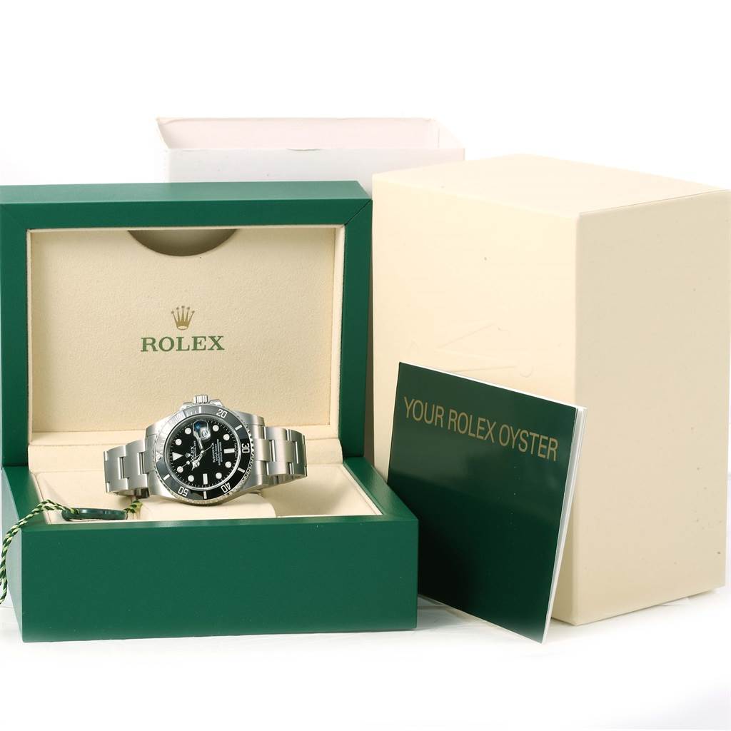 The image shows a Rolex Submariner 116610 Men
s Stainless Steel Black Dial 116610 Men
s Stainless Steel Black Dial watch in its case along with its box and booklet from a straight-on angle.